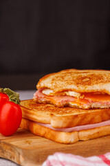 Hearty Cheese and Ham Sandwiches with Cherry Tomatoes on a Black Concrete Table