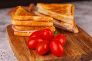 Savory Ham and Cheese Sandwich and Cherry Tomatoes on a Dark Cutting Board