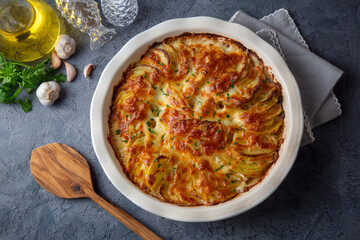 Potato gratin - graten (baked potatoes with cream and cheese) with rosemary and forks (Turkish name; Kremali patates)