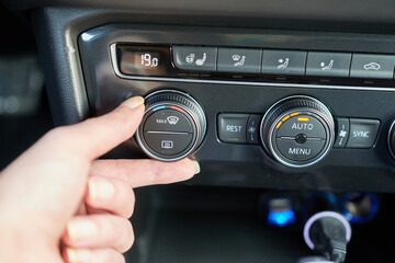 Close-up of female hand adjusting the air conditioning in a car