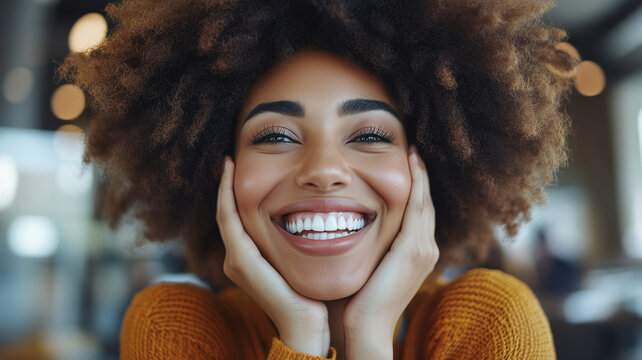 joyful woman with curly hair smiles brightly, showcasing her happiness in cozy cafe setting. Her warm expression radiates positivity and warmth