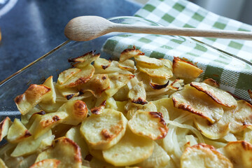 Fried potatoes with onions and garlic in a glass dish on the table