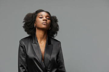Elegant confident woman in black blazer against a neutral background, embodying professionalism and...