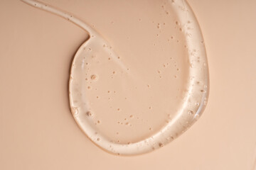 Liquid gel smear isolated on beige background. Beauty cosmetic smudge such as pure transparent aloe lotion, facial jelly serum, cleanser, shower gel or shampoo top view.