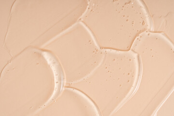 Cosmetic gel or beauty jelly serum texture background. Transparent skin care collagen product backdrop. Antibacterial sanitizer or liquid water moisture toner smudged smear, beige background