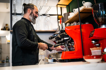 Professional barista in black apron working in restaurant. Portrait of happy barmen who is making coffee in his bar.