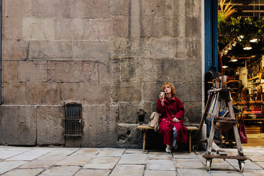 Tourist spending leisure time sitting and drinking coffee outside cafe