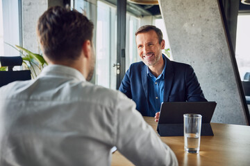 Smiling businessman taking interview of candidate at desk in office