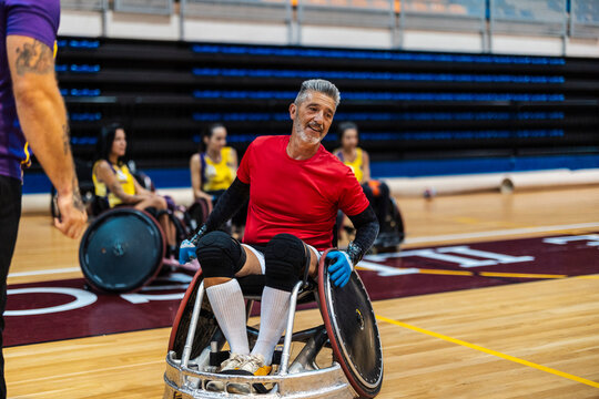 Senior man sitting in wheelchair and playing rugby at sports center