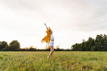 Cheerful woman walking on grass in meadow