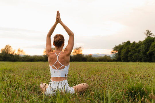 Woman sitting in prayer pose at meadow
