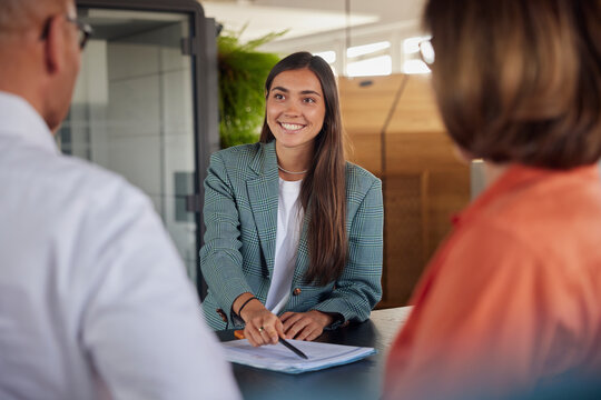 Smiling young business woman explaining documents at office
