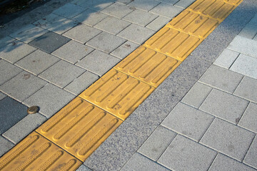 Gray block sidewalks and yellow tactile paving blocks for the visually impaired in Korea.