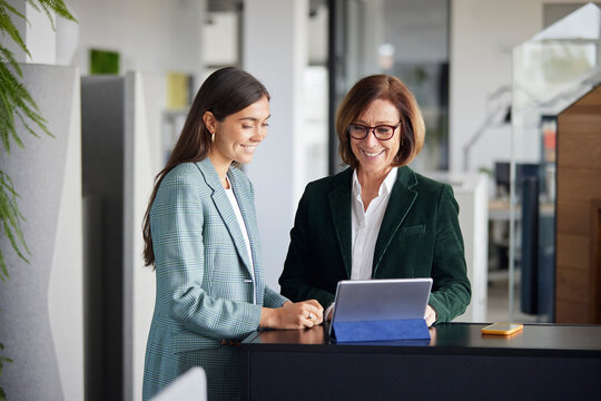 Cheerful business woman with employee using tablet PC at office