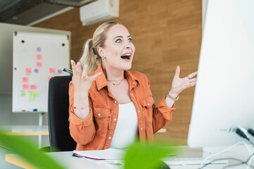 Surprised businesswoman talking on video call through computer in office