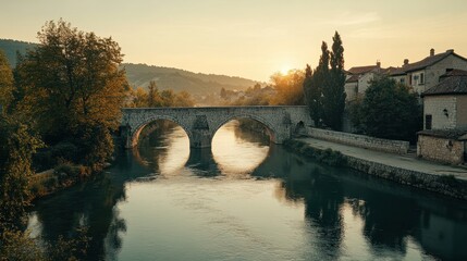 Obraz premium Tranquil Sunrise Over Old Stone Bridge and River in a Historic Town