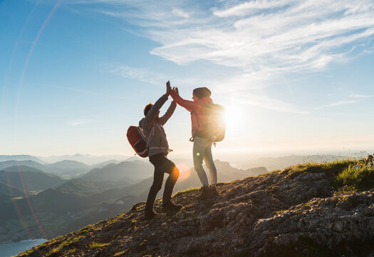 Happy couple giving high five to each other on top of mountain