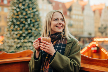 Blond woman holding mug of hot drink at Christmas market