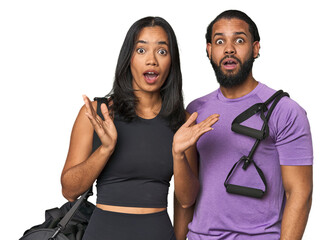 Young Latino couple ready for gym training surprised and shocked.
