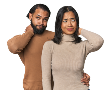 Young Latino couple in studio touching back of head, thinking and making a choice.