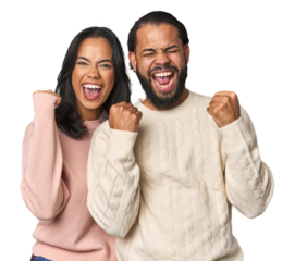 Young Latino couple in studio cheering carefree and excited. Victory concept.