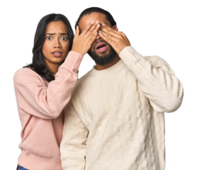 Young Latino couple in studio afraid covering eyes with hands.