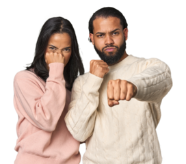 Young Latino couple in studio throwing a punch, anger, fighting due to an argument, boxing.