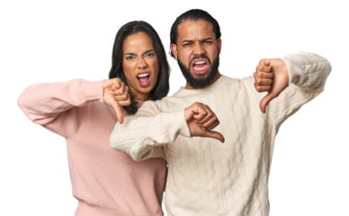 Young Latino couple in studio showing thumb down and expressing dislike.