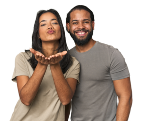 Young Latino couple in studio folding lips and holding palms to send air kiss.