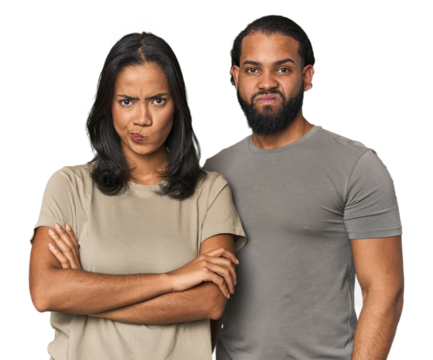 Young Latino couple in studio frowning face in displeasure, keeps arms folded.