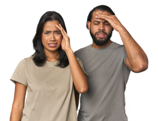 Young Latino couple in studio forgetting something, slapping forehead with palm and closing eyes.