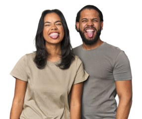 Young Latino couple in studio funny and friendly sticking out tongue.
