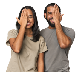 Young Latino couple in studio having fun covering half of face with palm.