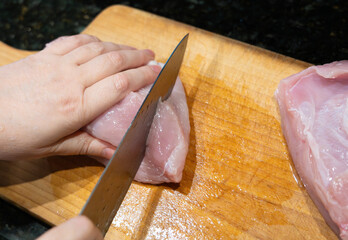 Raw turkey fillet slicing for nuggets or escalope, cut meat with kitchen knife, homemade schnitzel