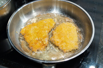 Frying schnitzel in hot oil in a steel pan, boiling oil with a piece of meat, cooking homemade schnitzel