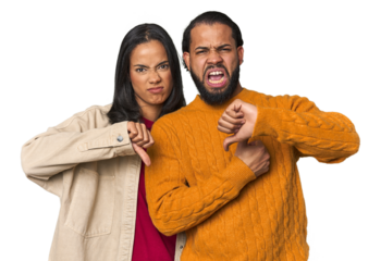 Young Latino couple in studio showing thumb down and expressing dislike.