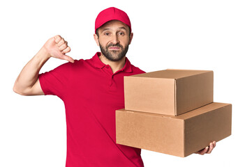 Hispanic male courier with boxes showing a dislike gesture, thumbs down. Disagreement concept.