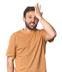 Studio portrait of young Hispanic male forgetting something, slapping forehead with palm and...