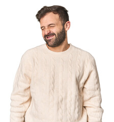 Fototapeta premium Studio portrait of young Hispanic male laughs and closes eyes, feels relaxed and happy.