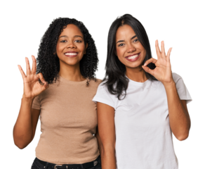 Young Latin friends in studio cheerful and confident showing ok gesture.