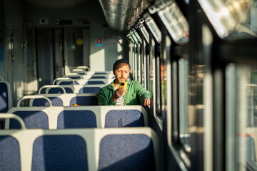 Focused man traveling to work on train with smartphone. Serious male commuting by train,...