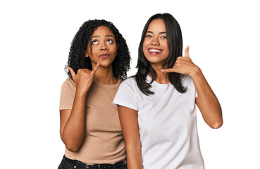 Young Latin friends in studio showing a mobile phone call gesture with fingers.