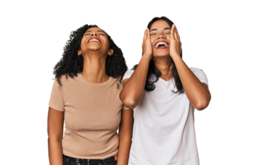 Young Latin friends in studio laughs joyfully keeping hands on head. Happiness concept.