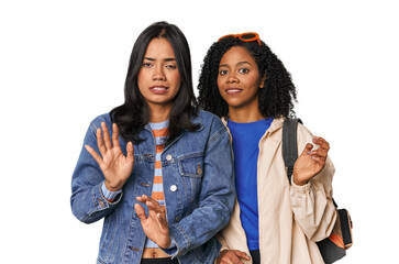 Latin friends ready for vacation rejecting someone showing a gesture of disgust.