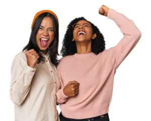 Young Latin friends together in studio raising fist after a victory, winner concept.