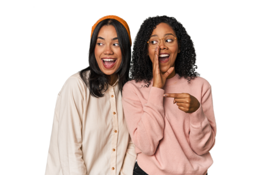 Young Latin friends together in studio saying a gossip, pointing to side reporting something.