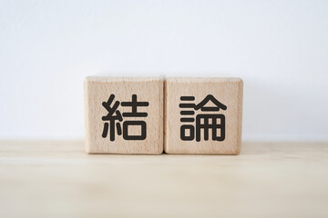木のブロックに結論と書いている