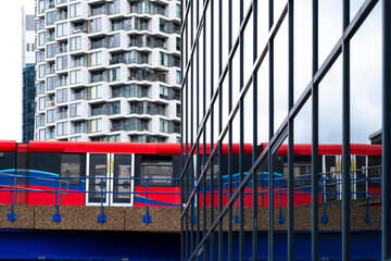 A vibrant red train reflecting against sleek glass buildings, encapsulating the essence of modern transportation intertwined with urban design in a captivating urban setting.