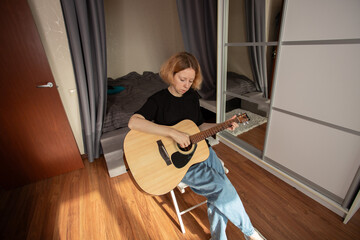 music lessons, Woman learning guitar, practicing chords on acoustic guitar, focusing on string...