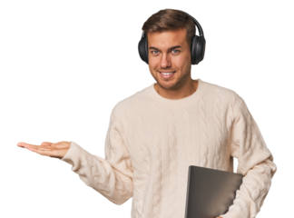 Young student man with a laptop showing a copy space on a palm and holding another hand on waist.
